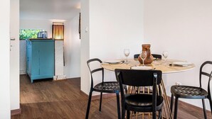 A dining area with a round table, black chairs, and a blue cabinet in the background. - Gîtes de France® - Le Gîte du Château (BERTREVILLE SAINT OUEN)