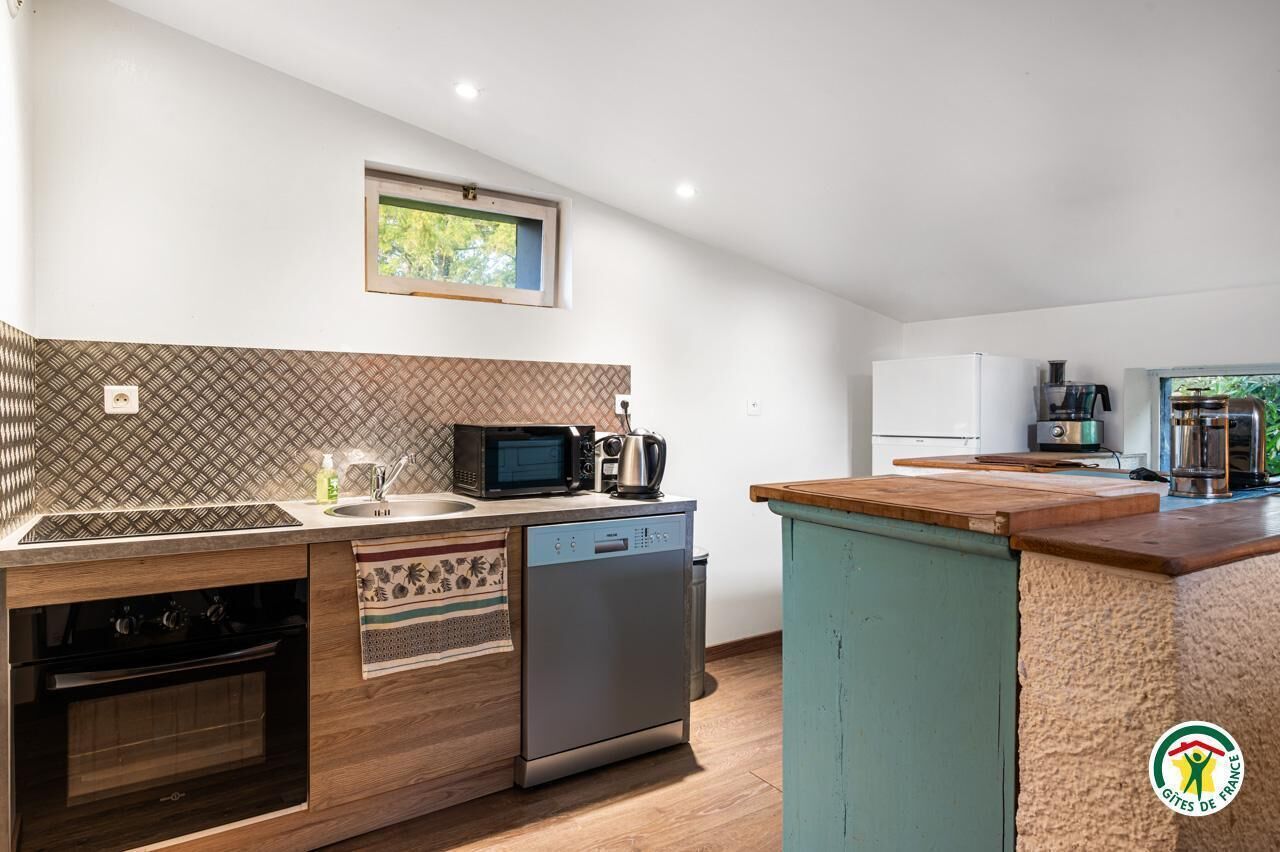 A modern kitchen with a dishwasher, microwave, and stove, a small window, and a view of the outdoors.
