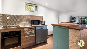 A modern kitchen with a dishwasher, microwave, and stove, a small window, and a view of the outdoors. - Gîtes de France® - Le Gîte du Château (BERTREVILLE SAINT OUEN)