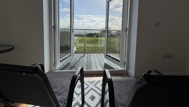 Ein Zimmer mit einer großen Schiebeglastür, die auf eine Terrasse im Freien führt.