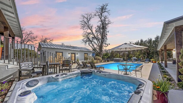 Vasca idromassaggio con piscina, area relax all'aperto e vista sul tramonto.