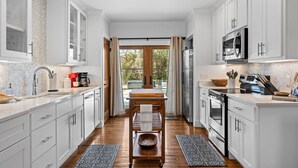 Una cucina moderna con mobili bianchi, un tavolo di legno e vista sull'esterno.