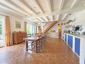 A spacious kitchen with a wooden table and chairs, a staircase, and a view of the outdoors. - Au coeur des Valades, private swimming pool (COUX ET BIGAROQUE)