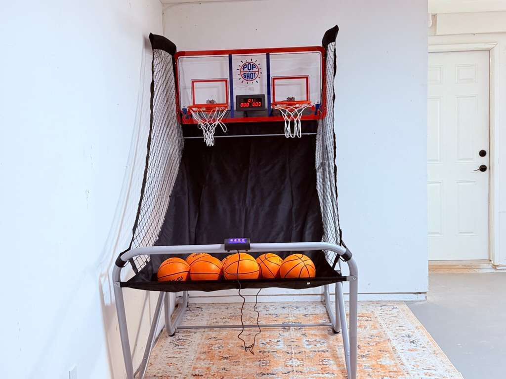Un petit terrain de basket intérieur, équipé d’un panier et d’un banc où sont rangés des ballons de basket.