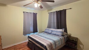 Ein Schlafzimmer mit einem Bett, einem Deckenventilator und Vorhängen.