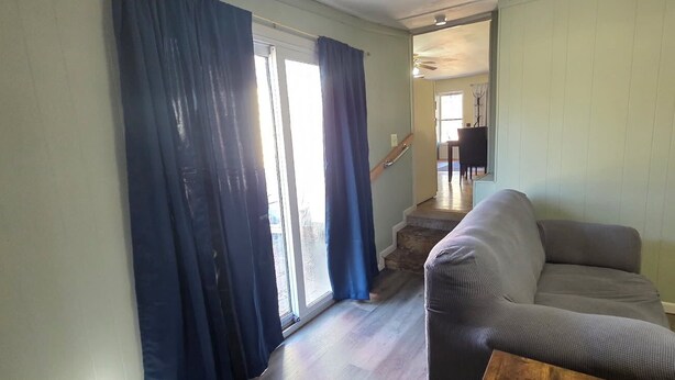 Ein Wohnzimmer mit grauem Sofa, einem Holztisch und einer Treppe, die in einen anderen Raum führt.