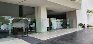 A modern building entrance with glass doors, a sign indicating 'SALIDA' (exit), and a motorized entrance. - La Palapa 1907: Frontal View of the Bay (Acapulco de Juárez)