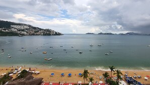Une plage où l’on peut voir de nombreux bateaux, une étendue de sable et, au loin, le paysage urbain.