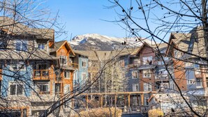 A row of multi-story buildings with a mountainous backdrop. - Elegant Mountain Retreat | Pool and Hot Tub (Canmore)