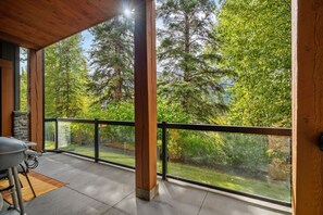 A covered outdoor area with a view of a forest. - Canmore Rockies Getaway| 2BR + Resort Amenities (Canmore)