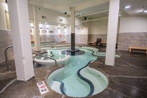 A spa area with a hot tub, a pool, and a bench. - Canmore Rockies Getaway| 2BR + Resort Amenities (Canmore)