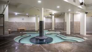 Una piscina con una fontana al centro, pareti piastrellate e una panchina.