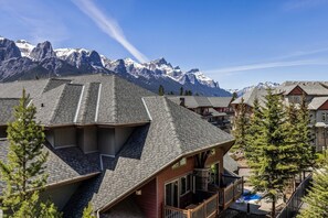 Eine Berglodge mit einem geneigten Dach, einem Balkon und Blick auf schneebedeckte Berge.