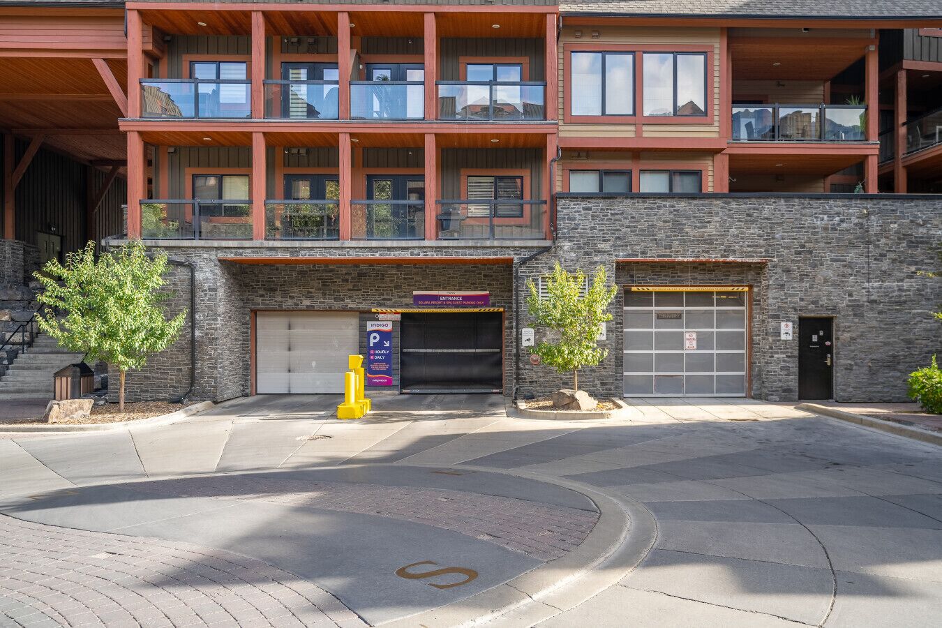 A modern building with a stone facade, a garage entrance, and a parking sign.