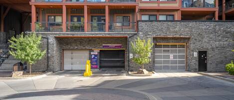 A modern building with a stone facade, a garage entrance, and a parking sign.