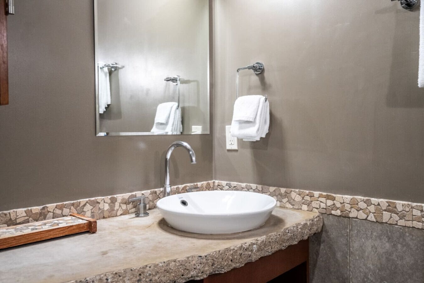 Un baño con lavamanos blanco, un espejo y un perchero para toallas.