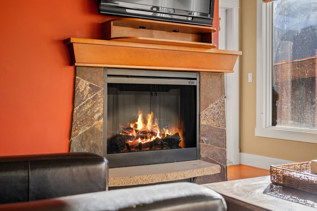 A fireplace with a TV on top, a stone surround, and a window to the right.