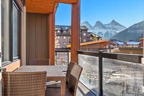 Un balcon agrémenté de meubles en osier, un plafond en bois et une vue sur des montagnes enneigées.