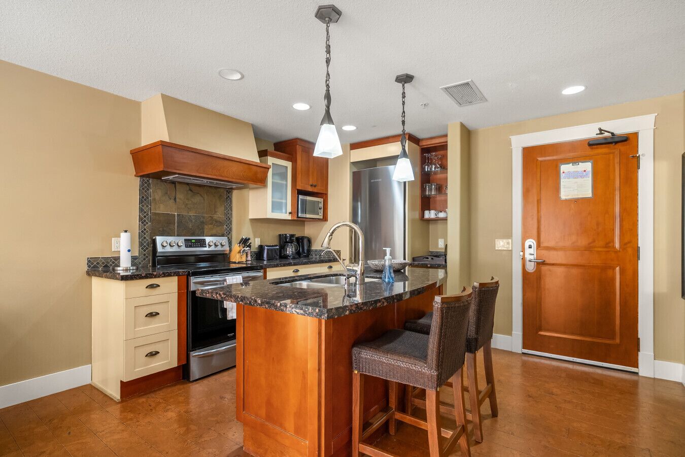 A kitchen with a central island, stainless steel appliances, wooden cabinets, and a built-in microwave.