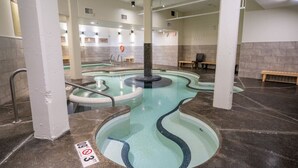 A spa area with a hot tub and a small pool, benches, and a sign indicating a height restriction. - Modern Condo Retreat 2BR+Sofa Bed | Patio & Trails (Canmore)