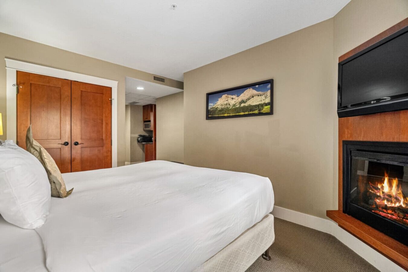 Une chambre d’hôtel avec un lit, une cheminée, une porte et un tableau encadré au mur.