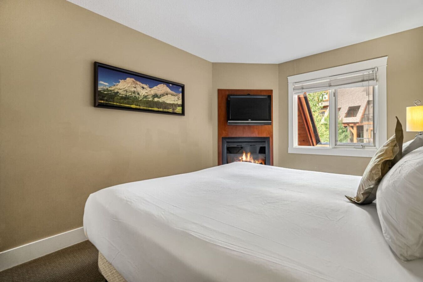 Een hotelkamer met een bed, een open haard, een televisie en een raam met gordijnen.
