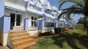 A multi-story hotel with balconies, a staircase leading to the entrance, and a well-maintained lawn. - 3-bed apartment, sea view - 6 guests (Denia)