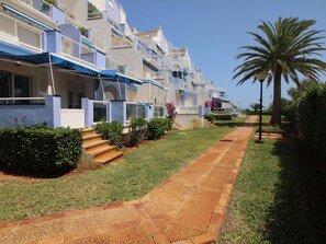 A row of modern, multi-story buildings with balconies, a well-maintained lawn, and a paved walkway. - 3-bed apartment, sea view - 6 guests (Denia)