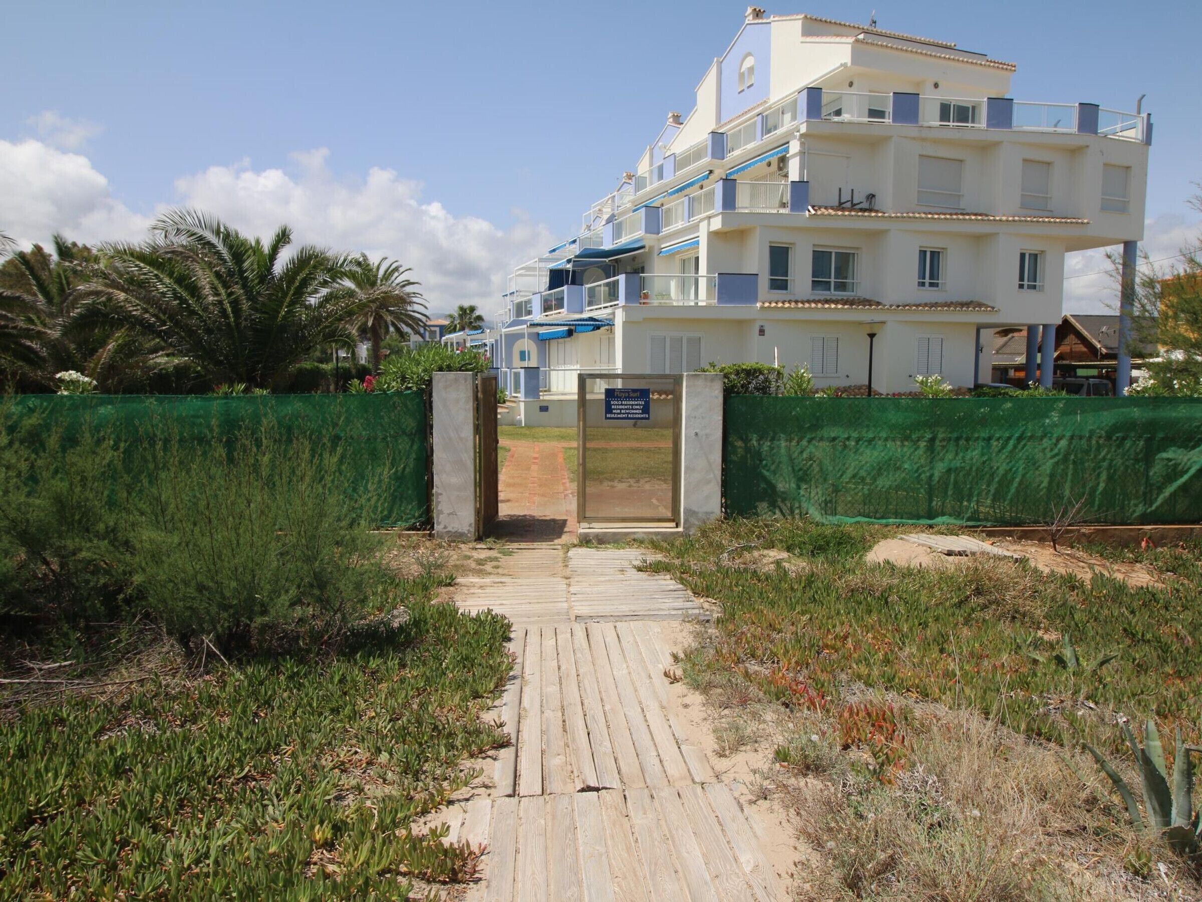A beachfront hotel with a wooden boardwalk leading to the entrance.