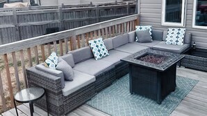 A covered outdoor seating area with a sofa, cushions, and a fire pit. - Lake Community Retreat - Family Parks (Calgary)