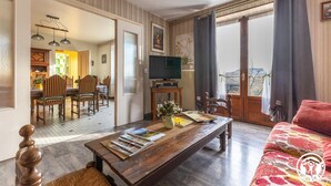 Ein Wohnzimmer mit Couch, Fernseher und einem Essbereich mit Stühlen und Tisch.