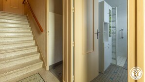 Ein Flur mit einer Treppe, die zu einem Zimmer mit Dusche und einer gläsernen Vitrine führt.