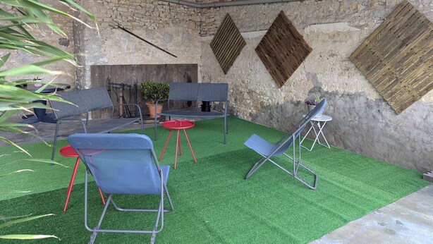 A rustic outdoor seating area with stone walls, a fire pit, and artificial grass. - Family home surrounded by nature - 6 guests (Courcelles-le-Roi)