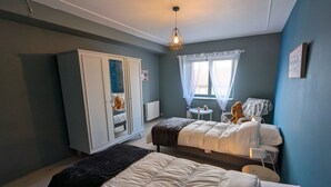 A bedroom with two beds, a wardrobe, a small table, and a window with curtains. - Family home surrounded by nature - 6 guests (Courcelles-le-Roi)