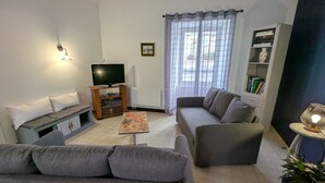 A living room with a sofa, a coffee table, a TV, and a bookshelf. - Family home surrounded by nature - 6 guests (Courcelles-le-Roi)
