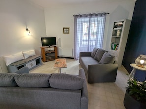 A living room with a sofa, a coffee table, a TV, and a bookshelf.