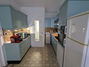 A compact kitchen with light blue cabinets, a stainless steel refrigerator, and a patterned floor.