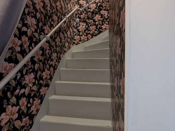 A staircase with white steps and a floral wallpaper on the walls.