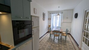 A compact kitchen with a dishwasher, oven, and a dining area with a table and chairs. - Family home surrounded by nature - 6 guests (Courcelles-le-Roi)