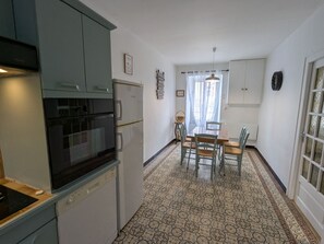 A compact kitchen with a dishwasher, oven, and a dining area with a table and chairs.