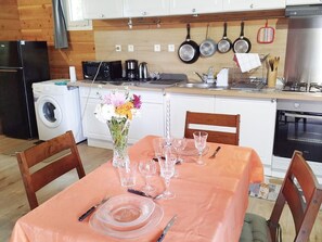 A compact kitchen with a dining area set for four. It includes a washing machine, a microwave, a coffee maker, and a stove.
