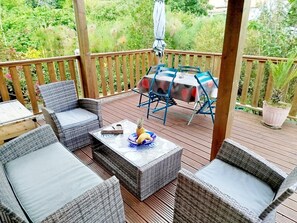 Eine überdachte Terrasse im Freien mit Korbmöbeln, einem Tisch mit Tischdecke und einem Blumentopf.