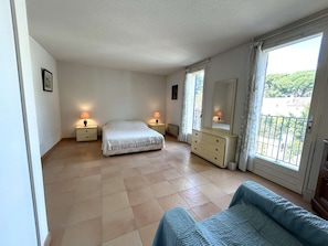 A bedroom with a bed, bedside tables, a dresser, a mirror, and a balcony with a view. - Apartment port view - 6 guests (Saint-Cyr-sur-Mer)