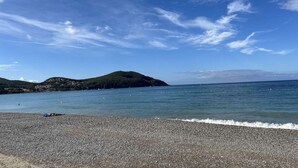 A pebbled beach with a clear sky and distant hills. - Apartment port view - 6 guests (Saint-Cyr-sur-Mer)