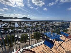 A balcony with a view of a marina, a table with glasses, and a bench. - Apartment port view - 6 guests (Saint-Cyr-sur-Mer)