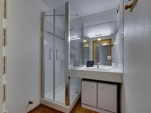 A modern bathroom with a glass-enclosed shower, a white sink, and a mirror above it. - Charming apartment, mountain view - 4 guests (Montvalezan-La Rosière)
