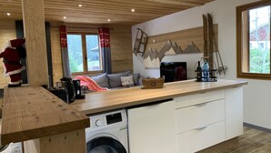 Una cucina compatta con lavatrice, piani di lavoro in legno e una finestra vista alberi.
