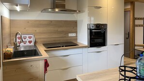 Una cucina moderna con cappa in acciaio inossidabile, forno integrato e lavello con piano in legno.