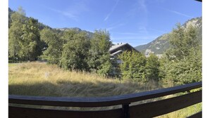 Vista da un’area coperta su un paesaggio montuoso, con un edificio in lontananza.