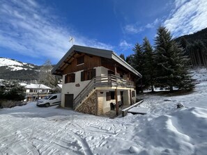 A two-story chalet with a wooden exterior, a balcony, and a ski lift nearby. - Spacious chalet - 10 guests (Châtel)